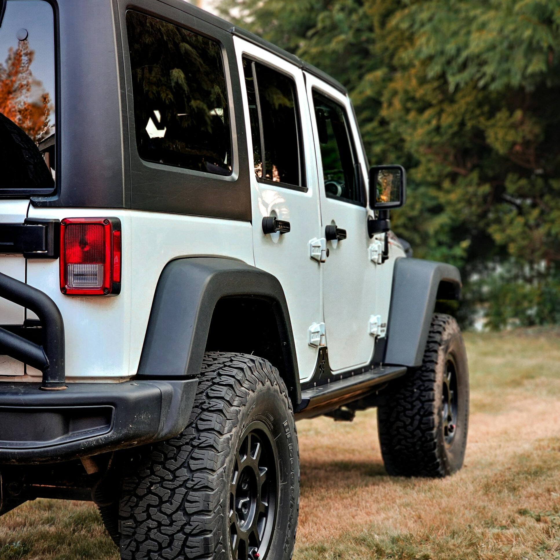 A rugged white Jeep Wrangler parked in a rural landscape, showcasing adventurous spirit.